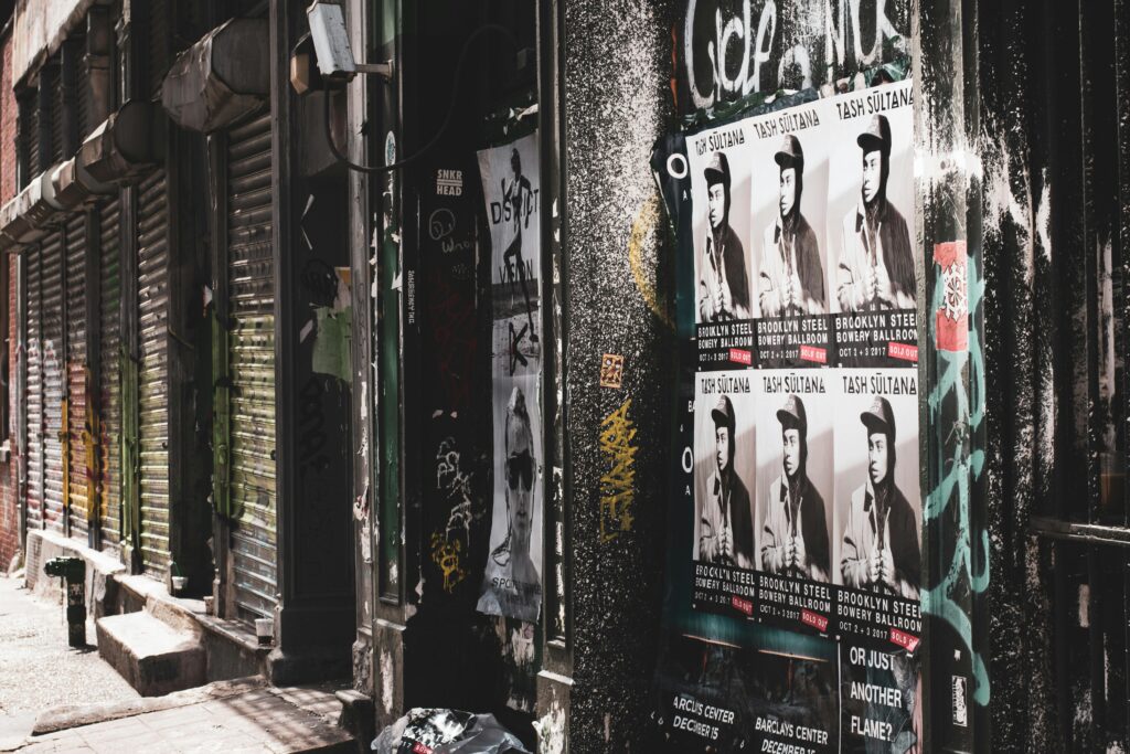 Gritty urban street shot in New York City featuring posters and graffiti in a deserted alleyway.