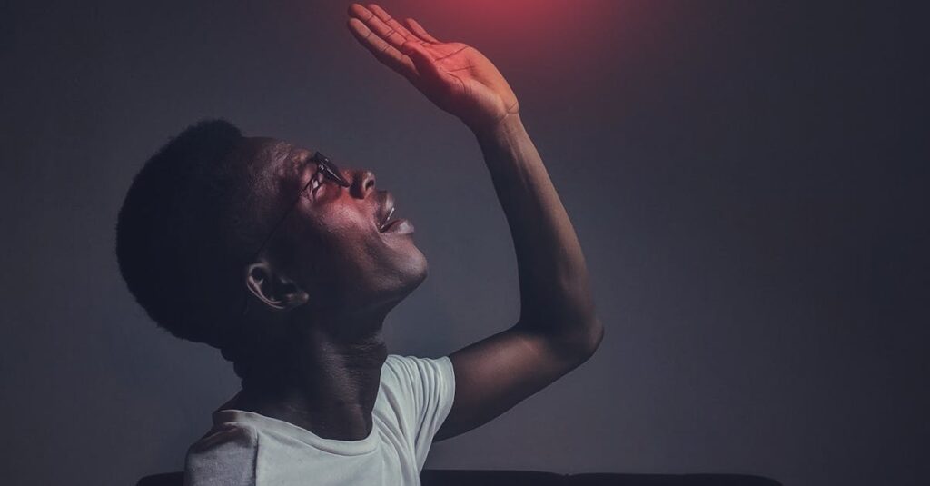 A man sits indoors reaching towards a glowing social media notification icon.